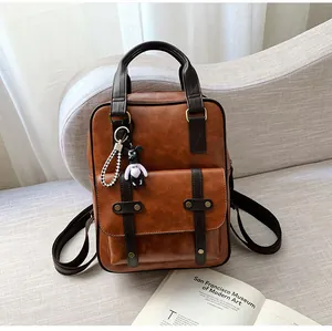 Detail of vintage brown leather backpack with rivet pocket and cute bear charm pendant