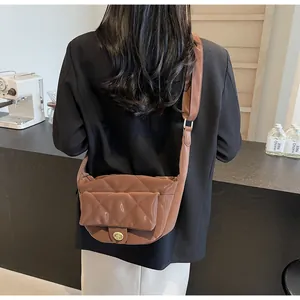 Detail of a brown quilted crossbody bag with golden metal twist lock and wide strap