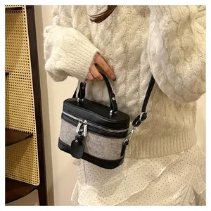 Detail of a chic cylindrical bucket bag showing mixed gray fabric and black leather texture