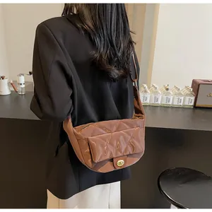 Close-up of brown quilted faux leather saddle bag with glossy finish and gold clasp