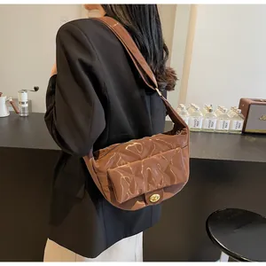 Brown quilted patent leather saddle bag detail with gold clasp and hobo strap