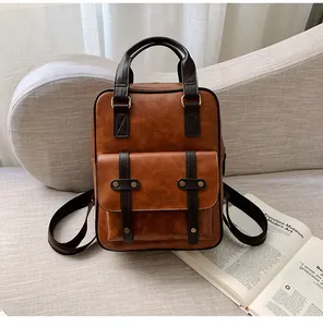 Detail of vintage brown leather backpack with bronze rivets and flap pocket on a sofa