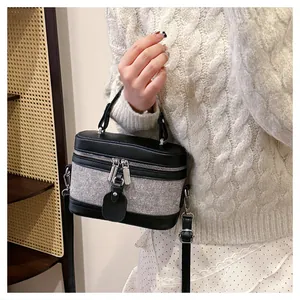Detail of a vintage box bag featuring grey textured fabric and black leather trim