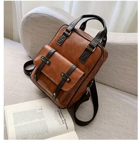 Detail view of vintage brown leather backpack with metal rivets on a grey sofa