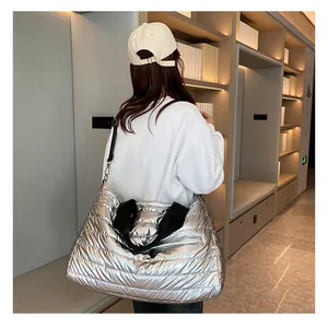 Sac de sport matelassé argenté porté en bandoulière élégante par un mannequin femme