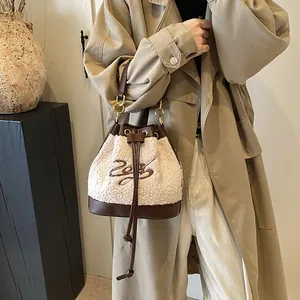 Fleece bucket bag with leather drawstring and metal handle on a stylish khaki outfit