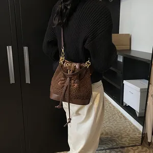 Brown plush bucket bag with artistic embroidery and leather trim shown in a lifestyle view