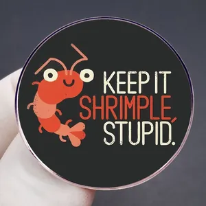 Funny cartoon lobster badge with Keep It Shrimple Stupid slogan in circular metal design