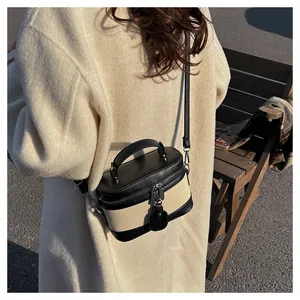 Chic two-tone box crossbody bag with leather handles shown on beige winter coat