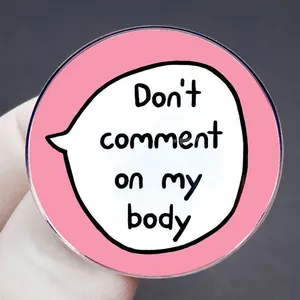 Pink round brooch with 'Don't comment on my body' text slogan and polished finish
