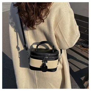 Outdoor close-up of a two-tone bucket bag with black leather and beige canvas details