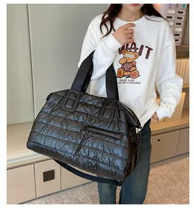 Vue détaillée du grand sac matelassé noir avec poignées larges et bandoulière réglable