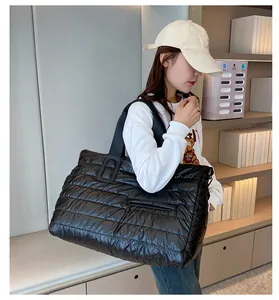 Detail of waterproof black quilted puffer tote with zip pocket and wide textile straps