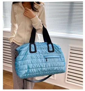 Sac de sport rembourré bleu avec poignées noires, porté par un mannequin en intérieur