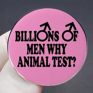 Pink round enamel pin with Why Animal Test slogan and male symbols on dark background
