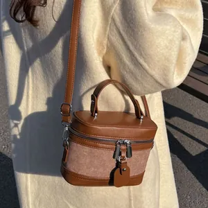 Chic vintage-inspired canvas and brown leather bucket bag shown as a stylish crossbody bag