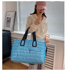 Close-up of a large blue quilted puffer tote bag with glossy waterproof nylon fabric