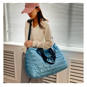 Detail of light blue quilted nylon fitness bag with sturdy black straps and large capacity