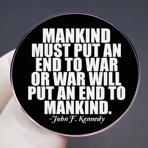 Round metal badge featuring JFK peace quote white text on black background