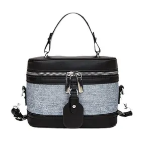 Minimalist denim and black leather vanity case handbag with a metal zipper and top handle