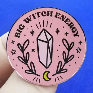 Broche Big Witch Energy avec cristaux et lune sur fond rose tenue en main