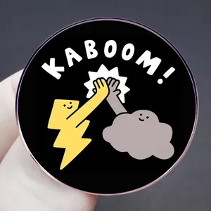 Cartoon Kaboom flash and cloud enamel pin badge on a black background held by hand