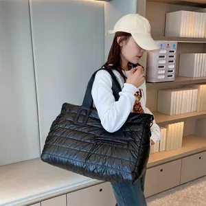 Large black quilted puffer tote bag for gym and travel shown on a model's shoulder