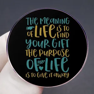 Runder Emaille-Pin mit Motivationsspruch, gehalten von einem Handschuh auf dunklem Grund