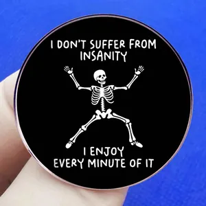 Funny skull enamel pin with I Don't Suffer From Insanity quote held between fingers