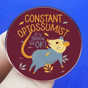 Constant Opossumist round metal brooch pin with motivational quote on blue background