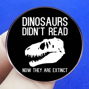 Round dinosaur skull enamel pin featuring the humorous quote Dinosaurs Didn't Read text