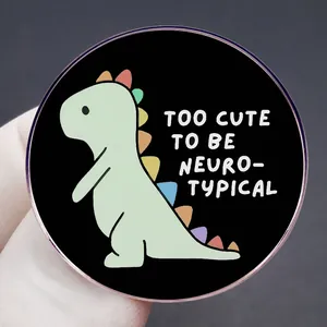 Spilla smaltata con dinosauro e scritta 'Too Cute To Be Neuro-Typical' su metallo nero