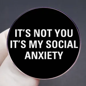 Round black enamel brooch pin featuring white It's Not You It's My Social Anxiety text