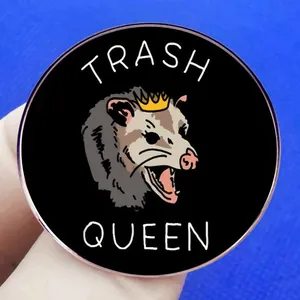 Cartoon opossum wearing a crown enamel pin badge with Trash Queen text on black base
