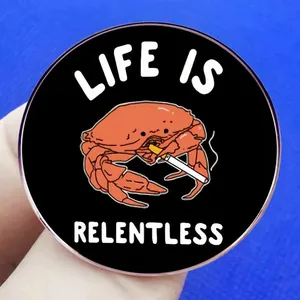 Schwarzer runder Emaille-Pin mit rauchender Krabbe und Life Is Relentless Slogan