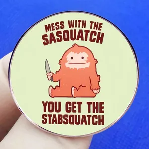 Αστεία καρφίτσα Sasquatch με μαχαίρι σε ανοιχτό πράσινο φόντο για ρούχα και τσάντες