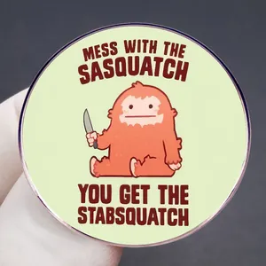 Στρογγυλή κονκάρδα Sasquatch με αστείο τέρας κινουμένων σχεδίων και μαχαίρι σε πράσινο φόντο
