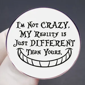 Cheshire Cat badge with I'M NOT CRAZY quote on white background in close-up hand view