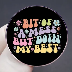 Enamel pin badge with 'BIT OF A MESS BUT DOIN' MY BEST' slogan on black round base