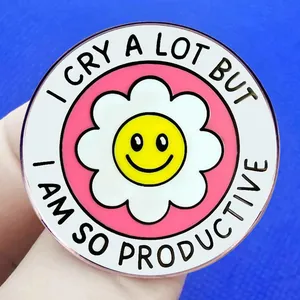 Pink enamel daisy pin with I CRY A LOT BUT I AM SO PRODUCTIVE quote in round metal badge