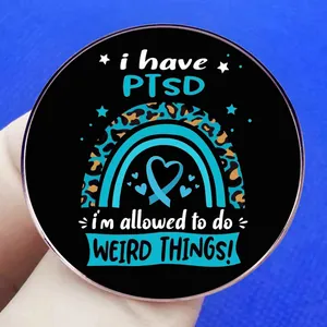 PTSD awareness badge with teal ribbon heart and weird things slogan on black base
