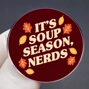 Round It's Soup Season Nerds enamel pin with autumn maple leaves on deep red background