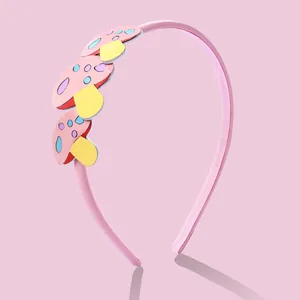 Détail d'un serre-tête rose pour enfants avec écussons champignons et dents antidérapantes