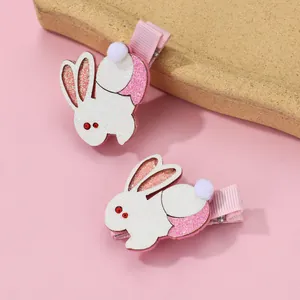 Close-up of pink and white glittery rabbit hair clips with white pom-pom details