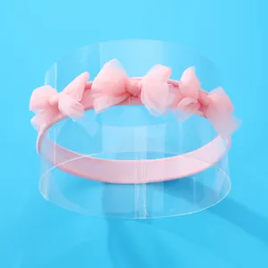 Bandeau élastique rose pour bébé avec trois nœuds en tulle sur un support d'affichage