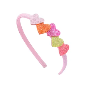 Pink girls headband with five colorful glitter heart ornaments on white background