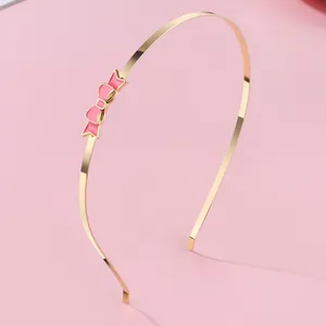 Detailansicht eines dünnen goldenen Metall-Haarreifs mit feinem rosa Emaille-Schmetterling