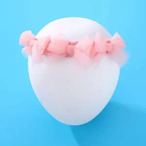 Bandeau bébé en tulle rose avec cinq nœuds sur support blanc et fond bleu clair
