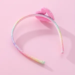 Rainbow glitter headband for girls featuring a pink plush heart on a pink background