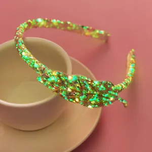 Détail d'un serre-tête vert pailleté avec motif de feuille et perles dorées pour filles